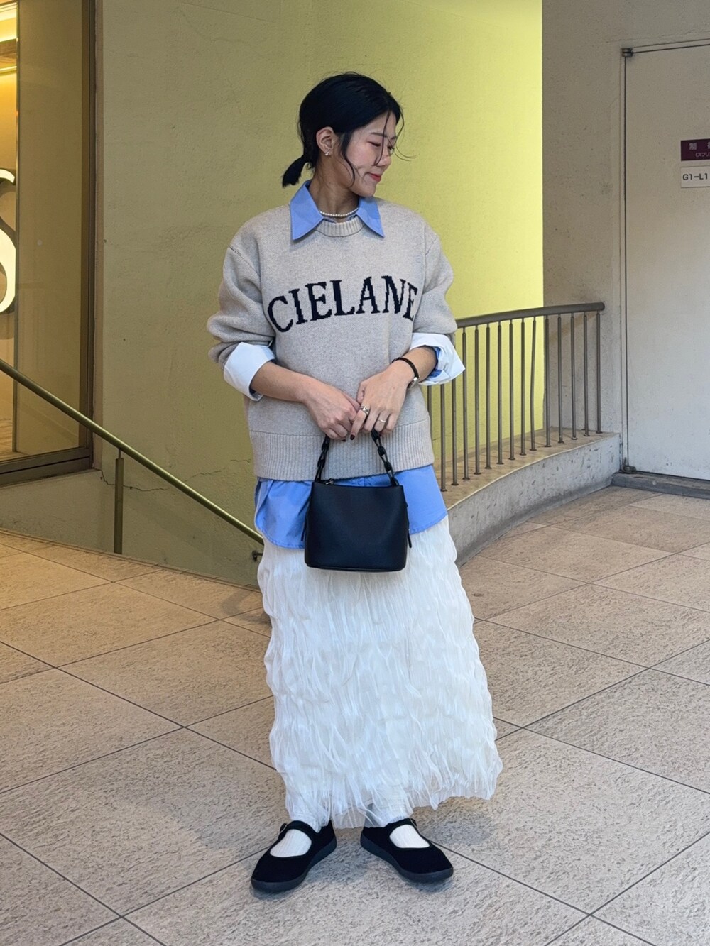 ブルー系のシャツ/ブラウス、ベージュ系のニット/セーター、ホワイト系のスカートを着用したレディースの冬コーディネートの2枚目の写真