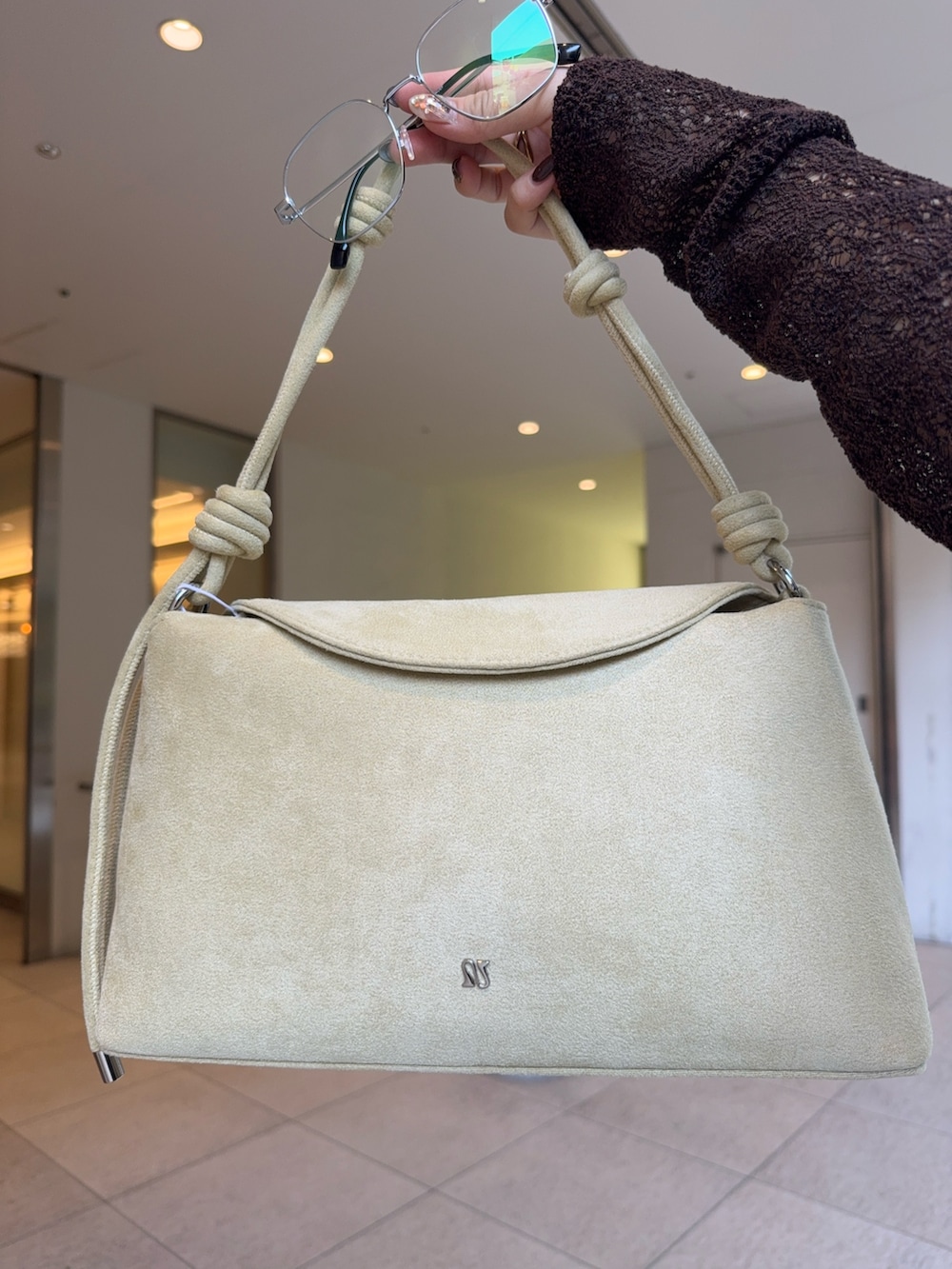 ベージュ系のハンドバッグ、ブルー系のデニムパンツ、ブラック系のその他シューズを着用したレディースの秋コーディネートの5枚目の写真
