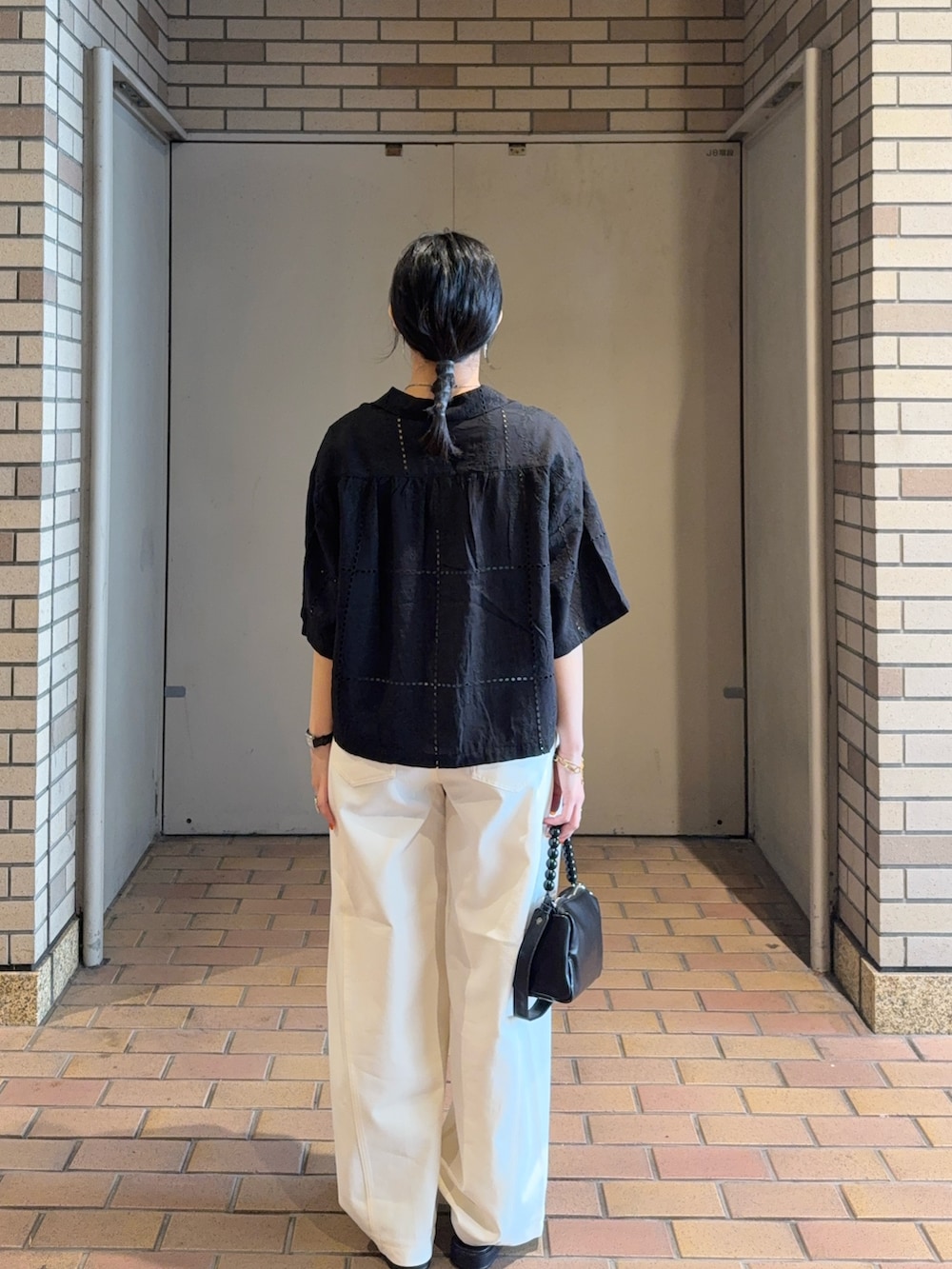 ブラック系のシャツ/ブラウス、ブラック系のショルダーバッグ、ホワイト系のその他パンツを着用したレディースの夏コーディネートの2枚目の写真