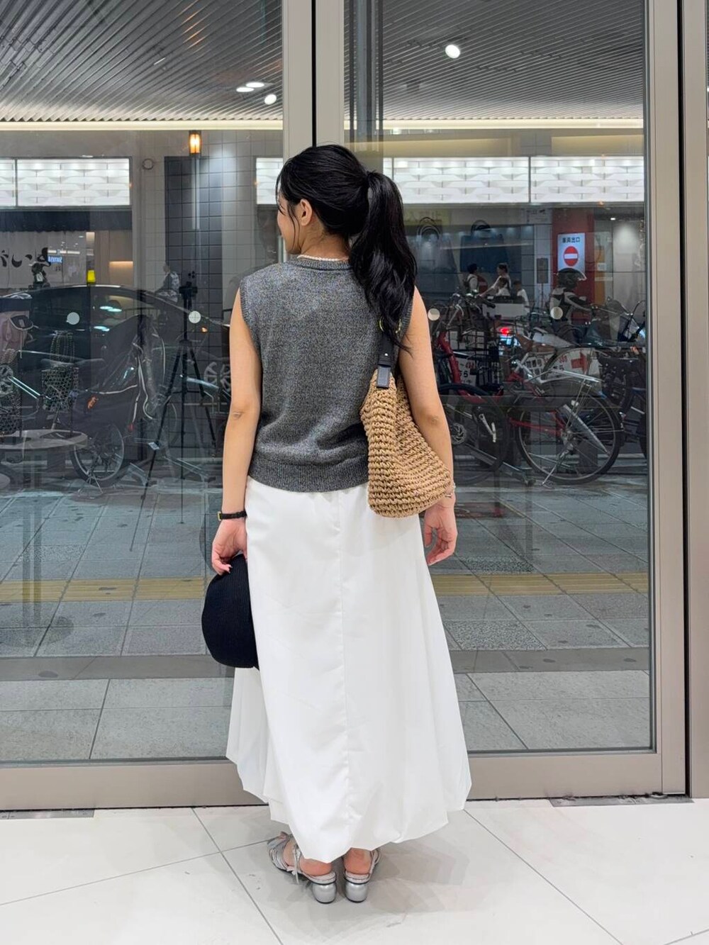イエロー系のトートバッグ、シルバー系のサンダル、ホワイト系のスカートを着用したレディースの夏コーディネートの2枚目の写真