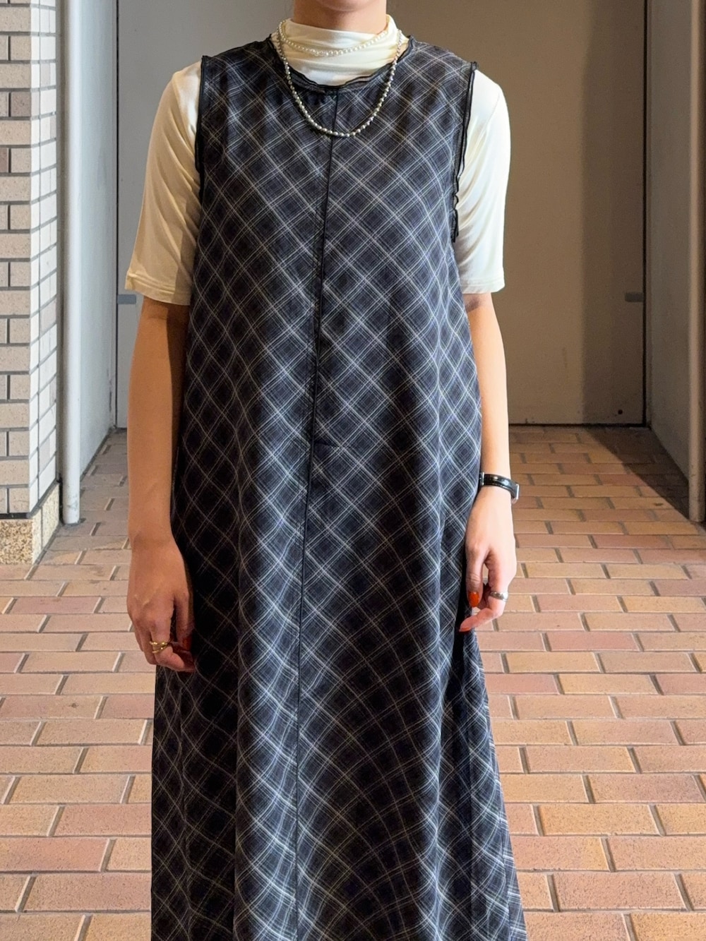 ブラック系のワンピース、ホワイト系のTシャツ/カットソー、ブラウン系のバレエシューズを着用したレディースの春コーディネートの2枚目の写真