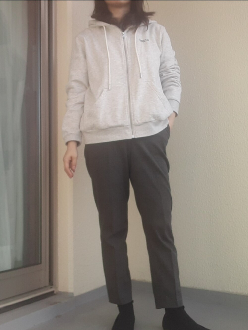 グレー系のパンツ、ブラック系のパンプス、グレー系のパーカーを着用したレディースの冬コーディネートの2枚目の写真