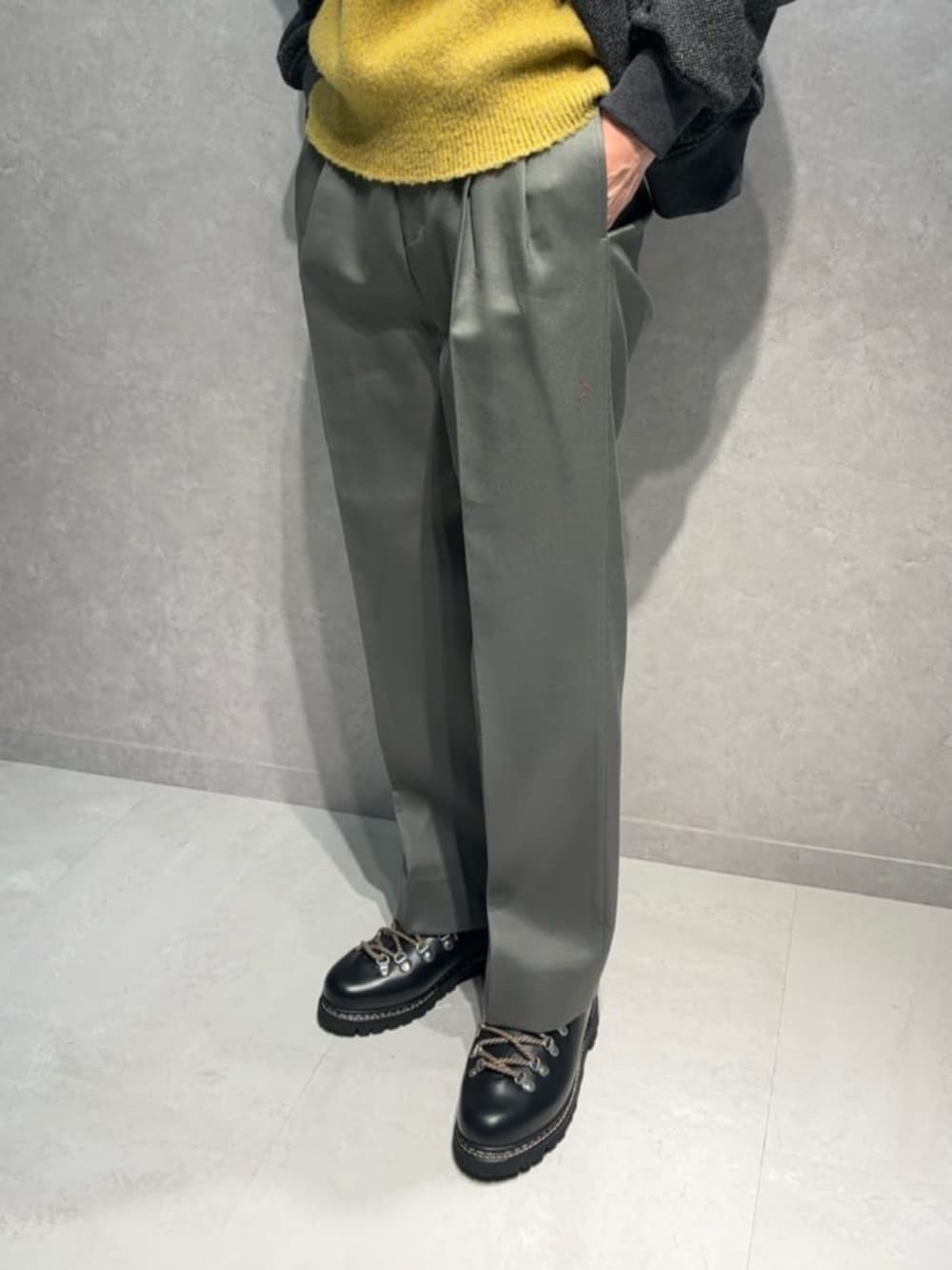 グレー系のスラックス、グリーン系のブルゾン、イエロー系のニット/セーターを着用したメンズの冬コーディネートの3枚目の写真