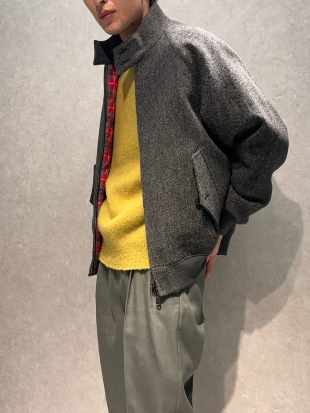 グレー系のスラックス、グリーン系のブルゾン、イエロー系のニット/セーターを着用したメンズの冬コーディネートの2枚目の写真