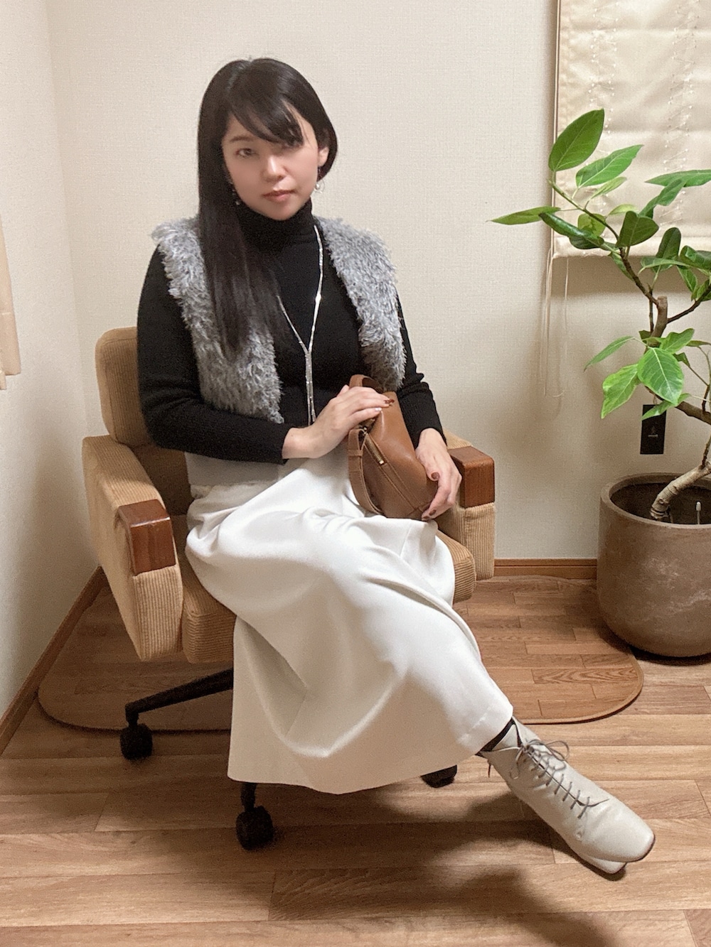 グレー系のベスト、ホワイト系のスカートを着用したレディースの冬コーディネートの3枚目の写真