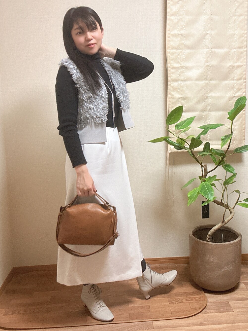 グレー系のベスト、ホワイト系のスカートを着用したレディースの冬コーディネートの2枚目の写真
