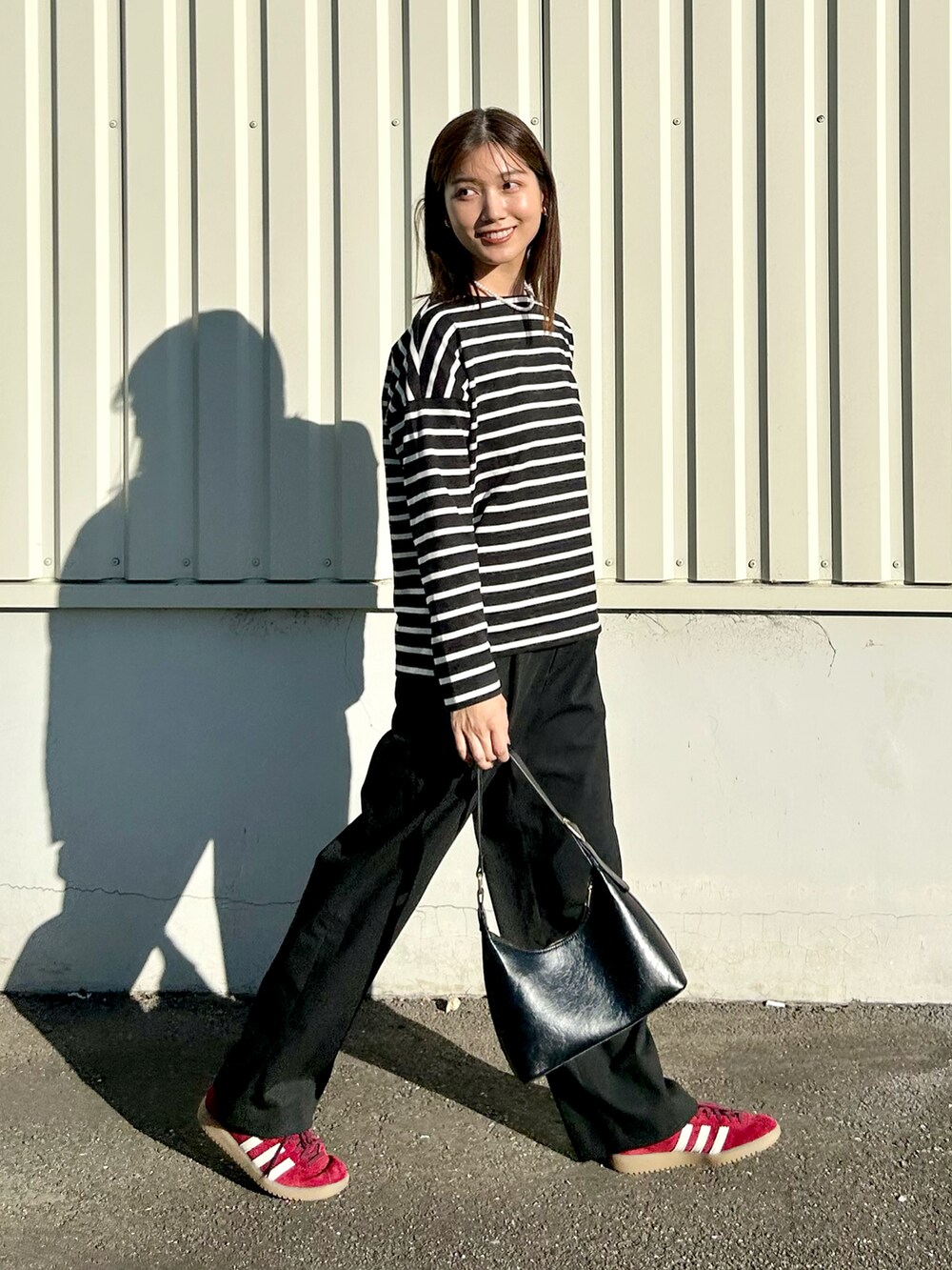 ブラック系のトップス、ブラック系のスラックス、レッド系のスニーカーを着用したレディースの秋コーディネートの4枚目の写真