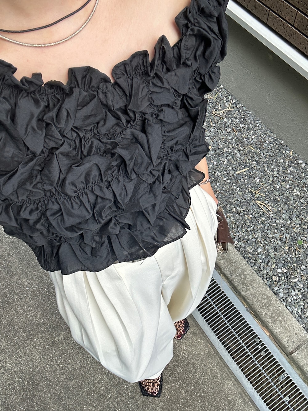 ブラック系のシャツ/ブラウス、ホワイト系のスラックス、ブラウン系のショルダーバッグを着用したレディースの夏コーディネートの2枚目の写真