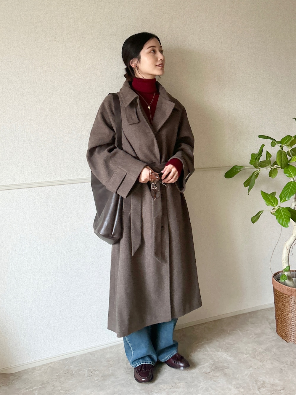 ブラウン系のステンカラーコート、レッド系のローファー、レッド系のニット/セーターを着用したレディースの冬コーディネートの3枚目の写真