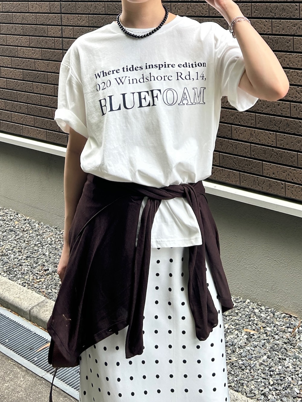 ホワイト系のスカート、ホワイト系のTシャツ/カットソー、ブルー系のデニムパンツを着用したレディースの春コーディネートの2枚目の写真