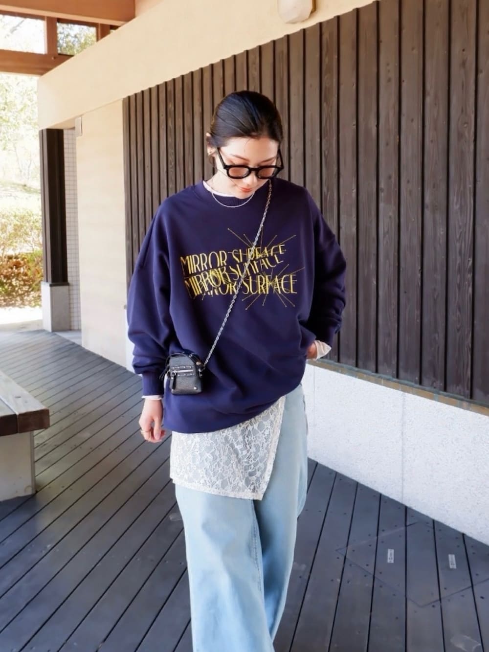 ブルー系のスウェット、ホワイト系のパンプス、ブラック系のポーチを着用したレディースの春コーディネートの5枚目の写真