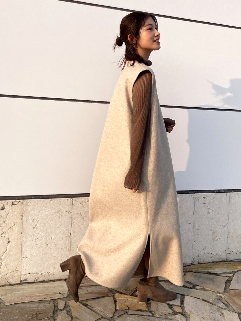 ベージュ系のワンピース、グレー系のTシャツ/カットソー、グレー系のブーツを着用したレディースの春コーディネートの2枚目の写真