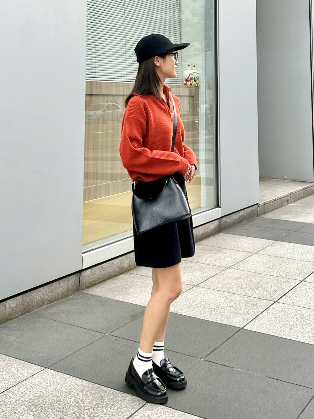 ブラック系のハンドバッグ、オレンジ系のニット/セーター、ブラック系のローファーを着用したレディースの秋コーディネートの3枚目の写真