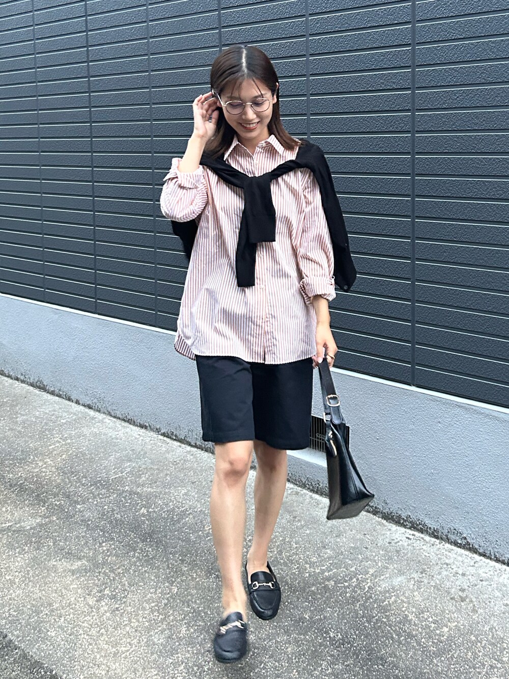 ブラック系のカーディガン/ボレロ、ブラック系のチノパンツ、ブラック系のハンドバッグを着用したレディースの秋コーディネートの2枚目の写真