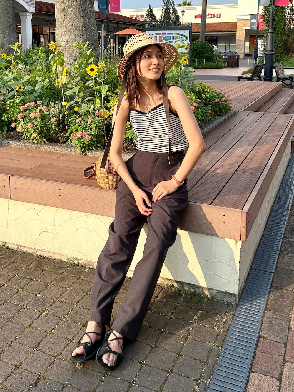 ホワイト系のアンサンブル、イエロー系のかごバッグ、グレー系のパンツを着用したレディースの夏コーディネートの3枚目の写真