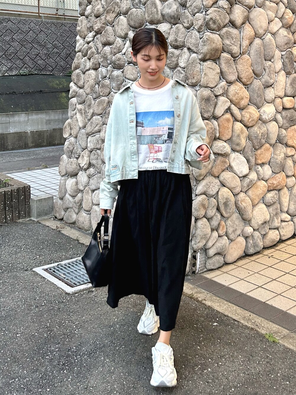 ブルー系のデニムジャケット、ホワイト系のTシャツ/カットソー、ブラック系のスカートを着用したレディースの秋コーディネートの2枚目の写真