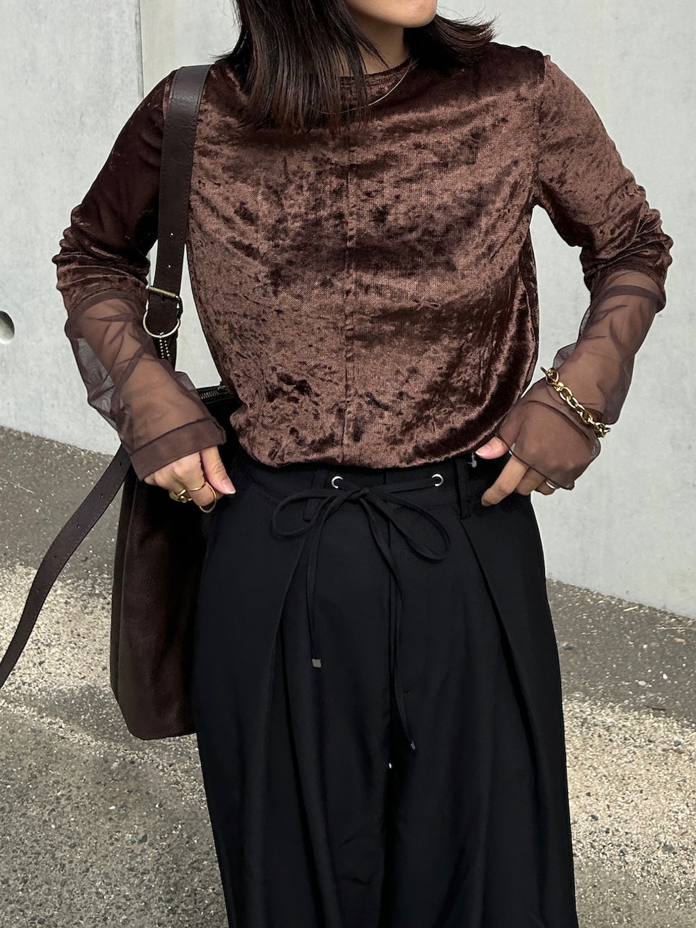 ブラック系のスラックス、ブラウン系のTシャツ/カットソー、ゴールド系のブレスレットを着用したレディースの秋コーディネートの2枚目の写真