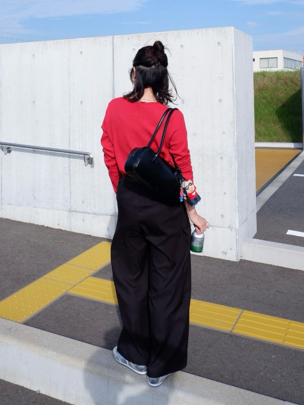 レッド系のTシャツ/カットソー、ブラック系のスラックス、シルバー系のスニーカーを着用したレディースの秋コーディネートの5枚目の写真