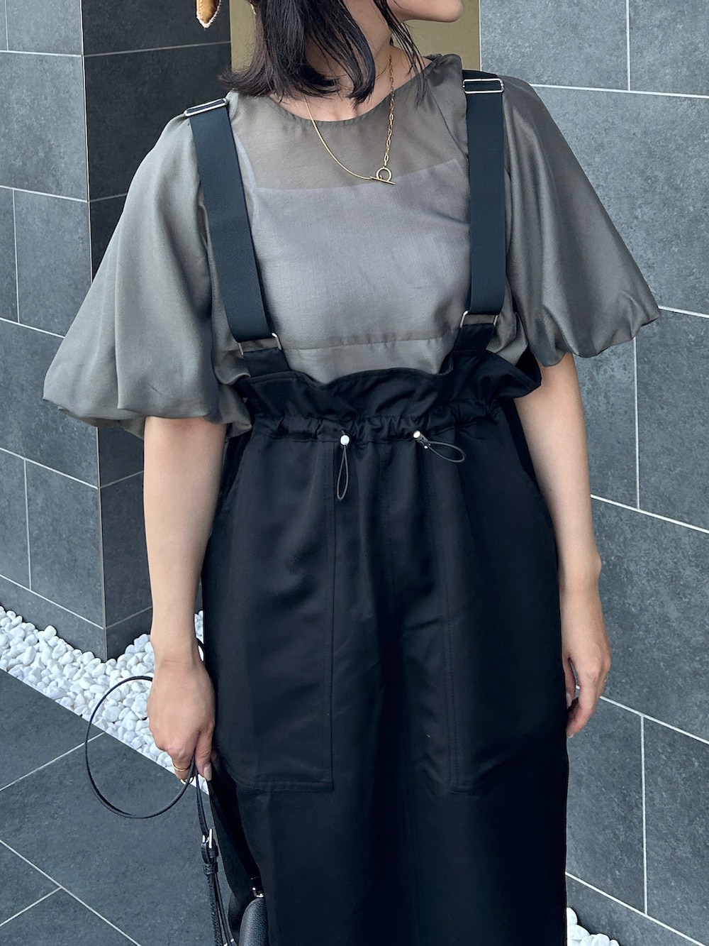 グレー系のシャツ/ブラウス、ブラック系のサンダル、ブラック系のジャンパースカートを着用したレディースの夏コーディネートの4枚目の写真