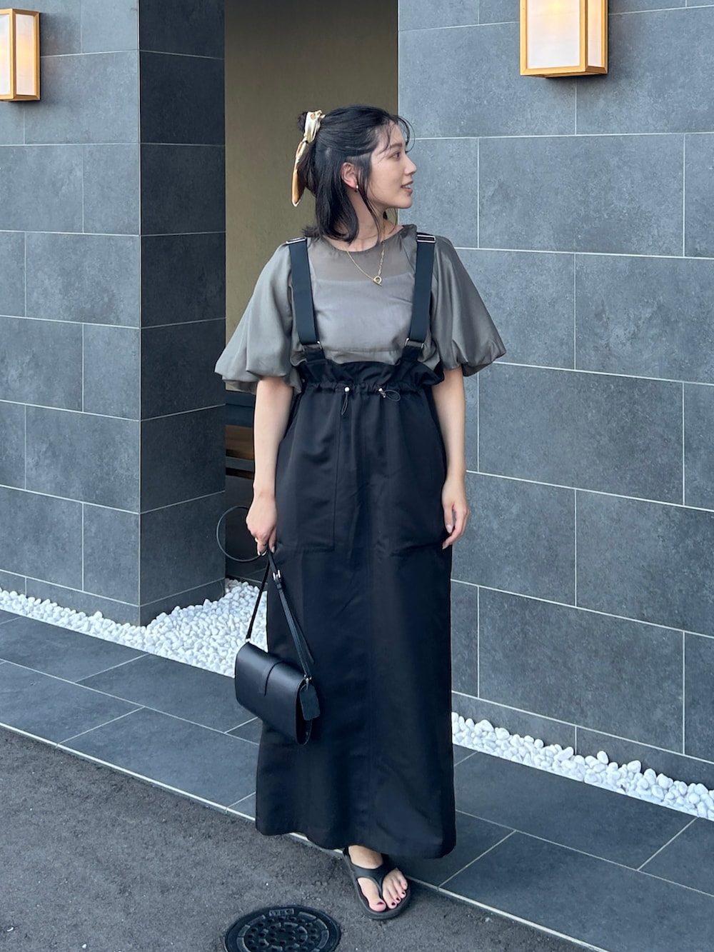 グレー系のシャツ/ブラウス、ブラック系のサンダル、ブラック系のジャンパースカートを着用したレディースの夏コーディネートの3枚目の写真
