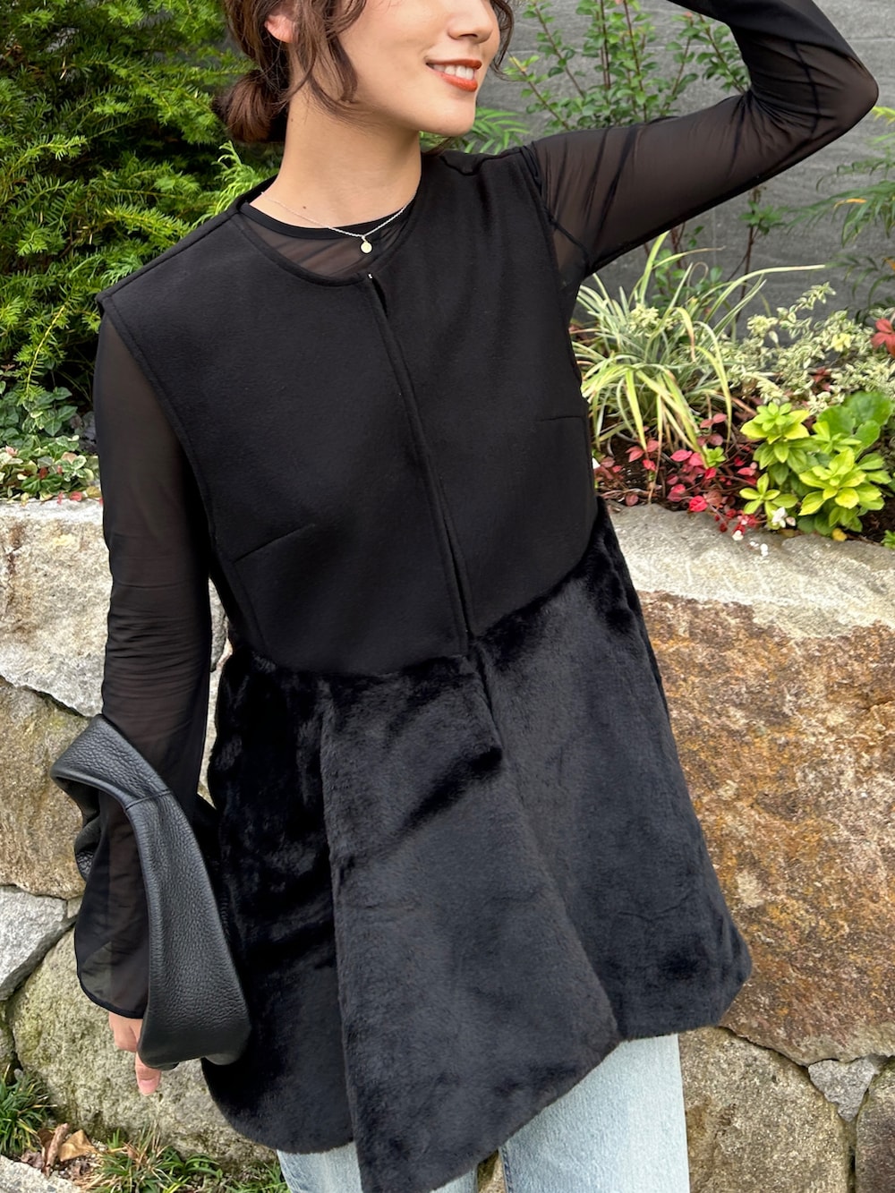 ブラック系のベスト、ブルー系のデニムパンツ、ブラック系のブーツを着用したレディースの秋コーディネートの4枚目の写真