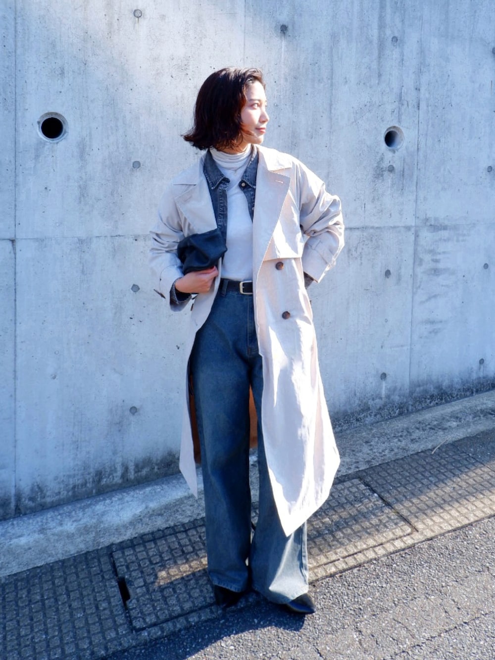 ホワイト系のトレンチコート、ブルー系のデニムパンツ、ブラック系のパンプスを着用したレディースの春コーディネートの2枚目の写真