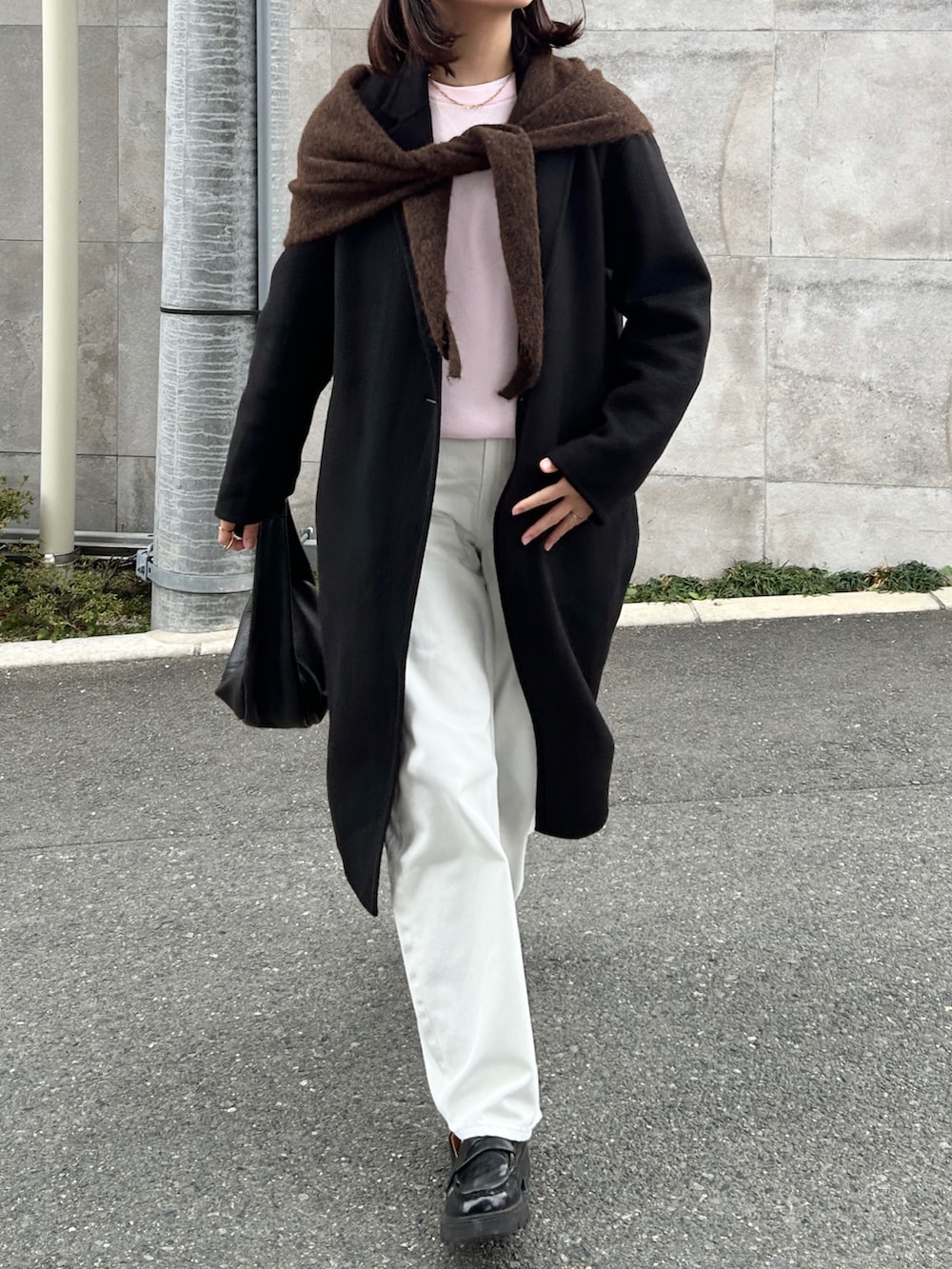 ブラック系のハンドバッグ、ブラック系のジャケット/アウター、ホワイト系のデニムパンツを着用したレディースの冬コーディネートの5枚目の写真