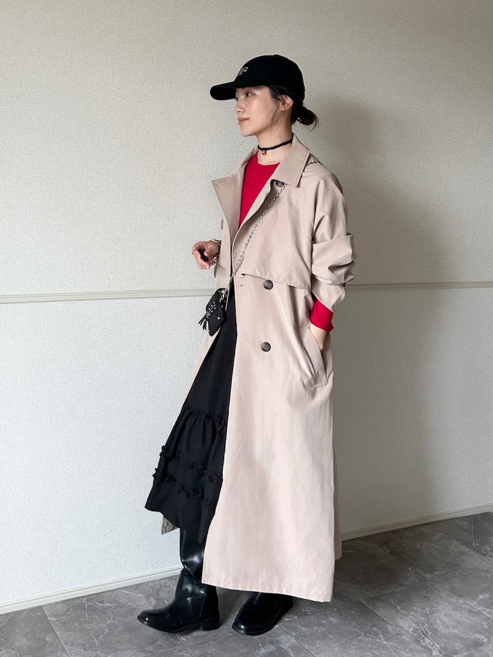 ベージュ系のトレンチコート、ブラック系のスカート、ブラック系のブーツを着用したレディースの春コーディネートの2枚目の写真