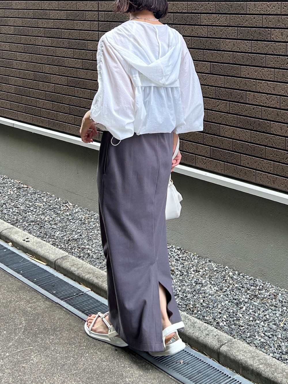 グレー系のワンピース、ホワイト系のマウンテンパーカー、ホワイト系のバッグを着用したレディースの夏コーディネートの2枚目の写真