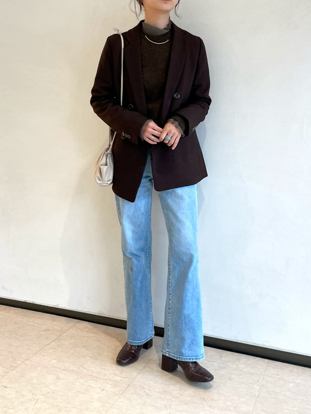 ブルー系のデニムパンツ、ブラウン系のテーラードジャケット、ブラウン系のニット/セーターを着用したレディースの春コーディネートの4枚目の写真
