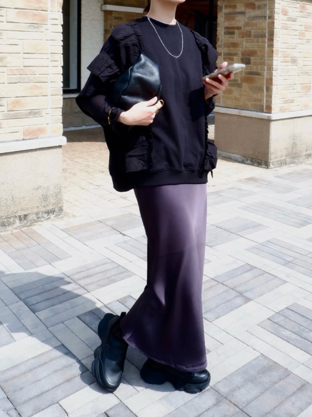 ブラック系のローファー、ブラック系のスウェット、ブラック系のハンドバッグを着用したレディースの春コーディネートの2枚目の写真