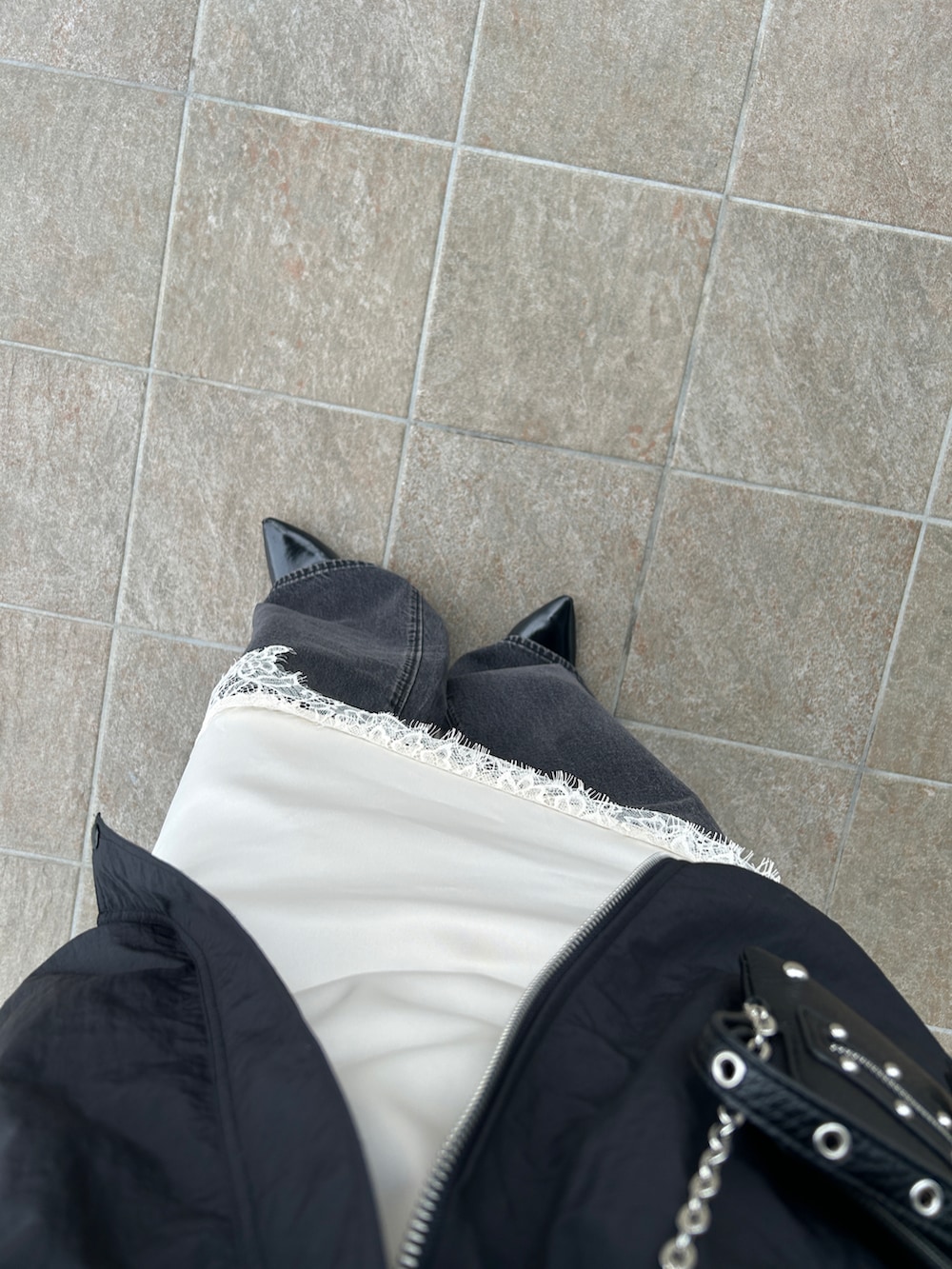 ホワイト系のキャミソール、ブラック系のナイロンジャケット、ブラック系のパンプスを着用したレディースの春コーディネートの5枚目の写真