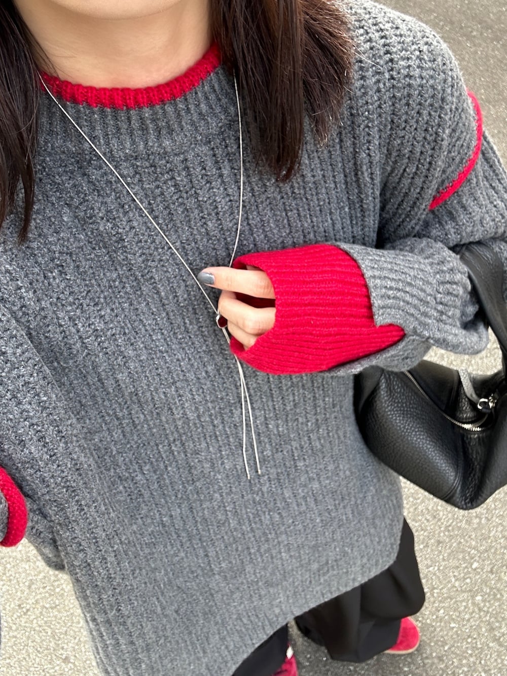 グレー系のニット/セーター、ブラック系のハンドバッグ、ブラック系のスラックスを着用したレディースの秋コーディネートの3枚目の写真