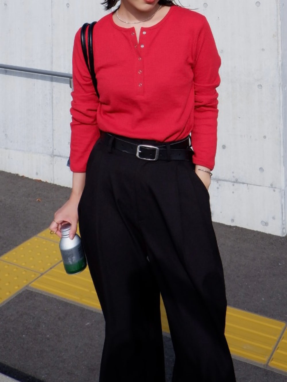 レッド系のTシャツ/カットソー、ブラック系のスラックス、シルバー系のスニーカーを着用したレディースの秋コーディネートの4枚目の写真