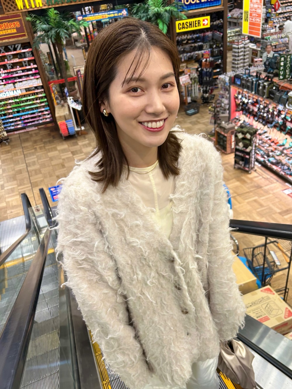 ホワイト系のカーディガン/ボレロ、ホワイト系のカーゴパンツ、ゴールド系のハンドバッグを着用したレディースの冬コーディネートの2枚目の写真