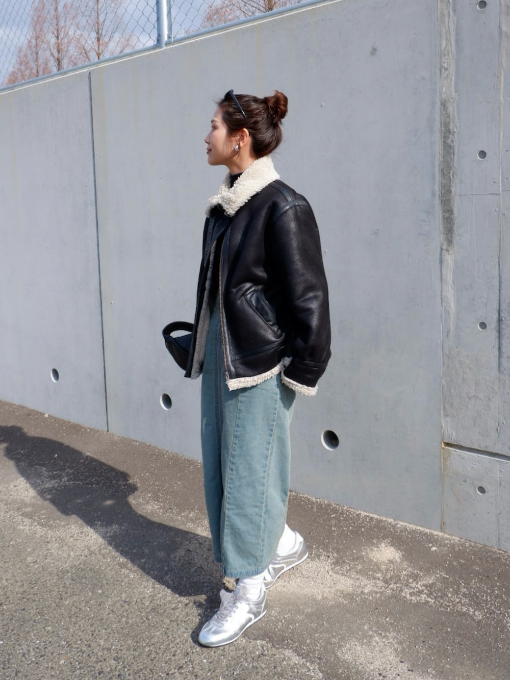 ブルー系のスカート、ブラック系のムートンコート、ブラック系のハンドバッグを着用したレディースの冬コーディネートの4枚目の写真