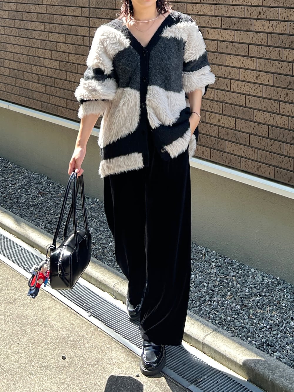 ブラック系のカーディガン/ボレロ、ブラック系のパンツ、ブラック系のローファーを着用したレディースの秋コーディネートの3枚目の写真