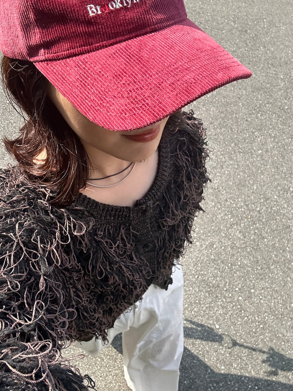 ブラック系のカーディガン/ボレロ、ブラウン系のショルダーバッグ、レッド系のスニーカーを着用したレディースの秋コーディネートの4枚目の写真