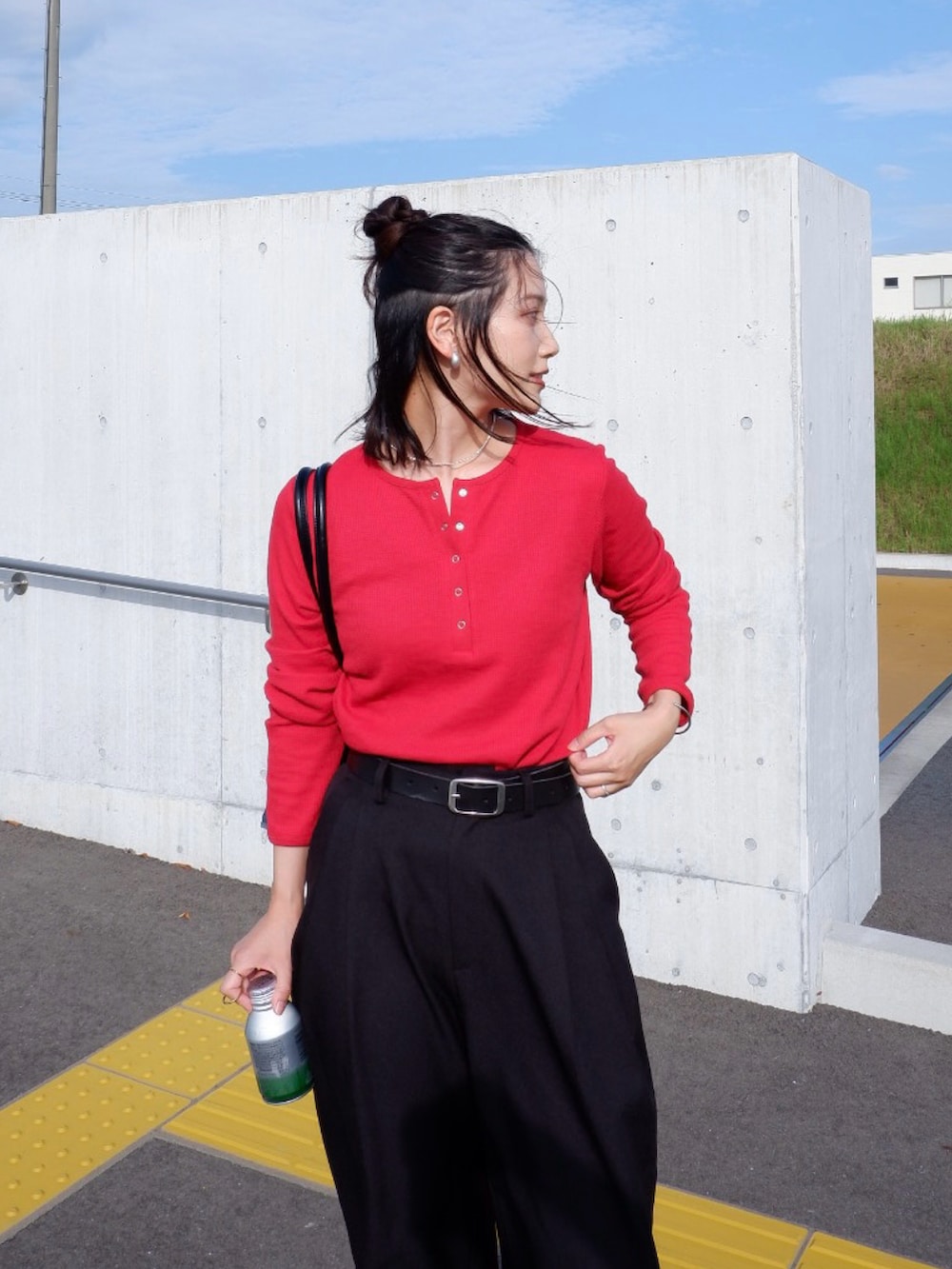 レッド系のTシャツ/カットソー、ブラック系のスラックス、シルバー系のスニーカーを着用したレディースの秋コーディネートの2枚目の写真
