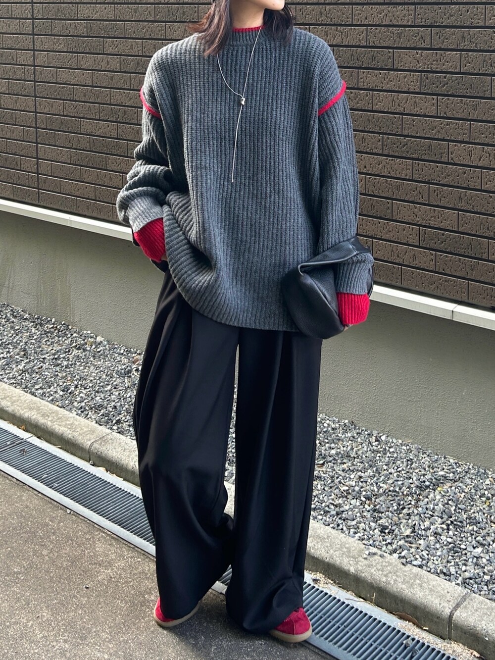 グレー系のニット/セーター、ブラック系のハンドバッグ、ブラック系のスラックスを着用したレディースの秋コーディネートの5枚目の写真