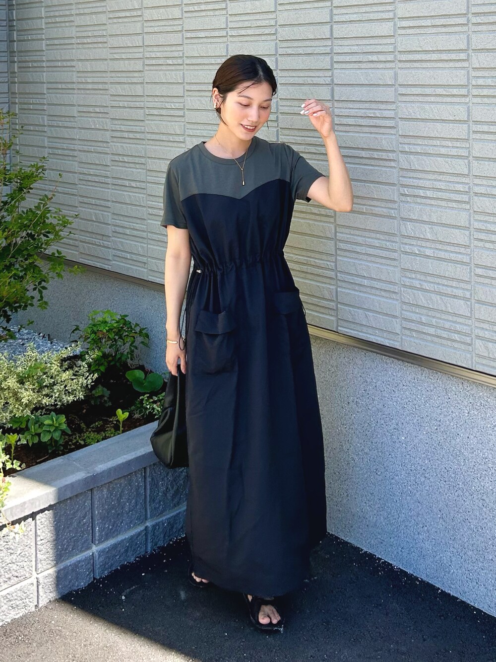 グレー系のワンピース、ブラック系のハンドバッグ、ブラック系のサンダルを着用したレディースの夏コーディネートの2枚目の写真