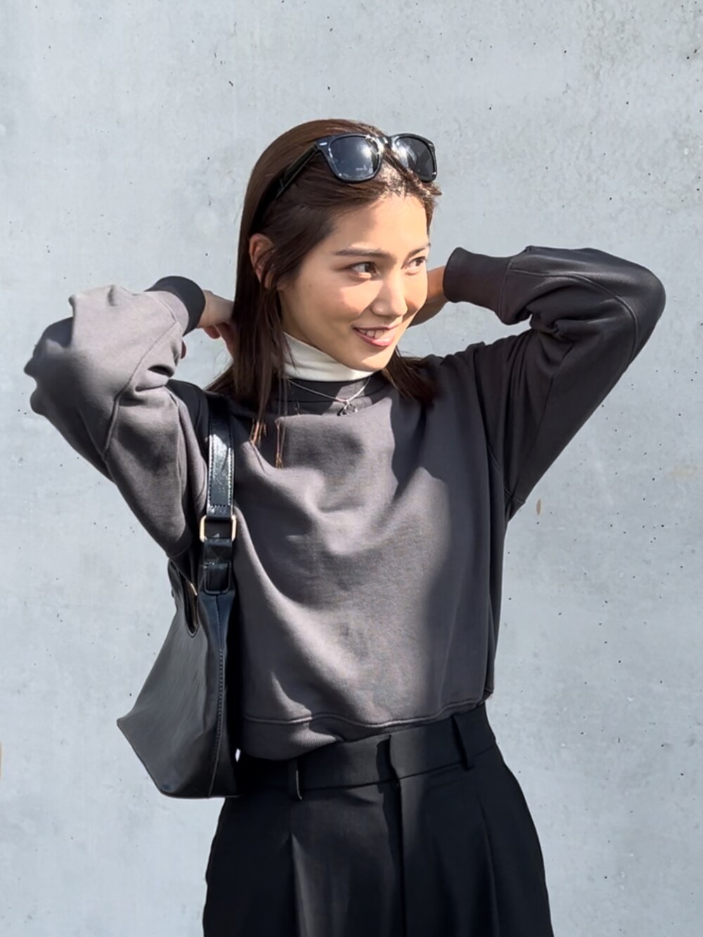 グレー系のトップス、ブラック系のスラックス、ブラック系のパンプスを着用したレディースの冬コーディネートの2枚目の写真