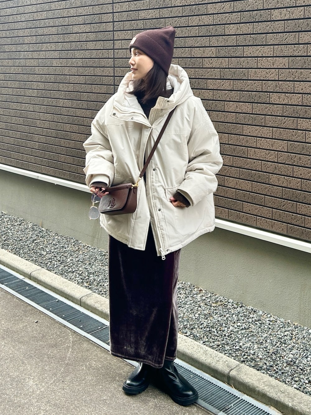 ホワイト系のブルゾン、ブラック系のブーツ、ブラウン系のニット/セーターを着用したレディースの冬コーディネートの4枚目の写真