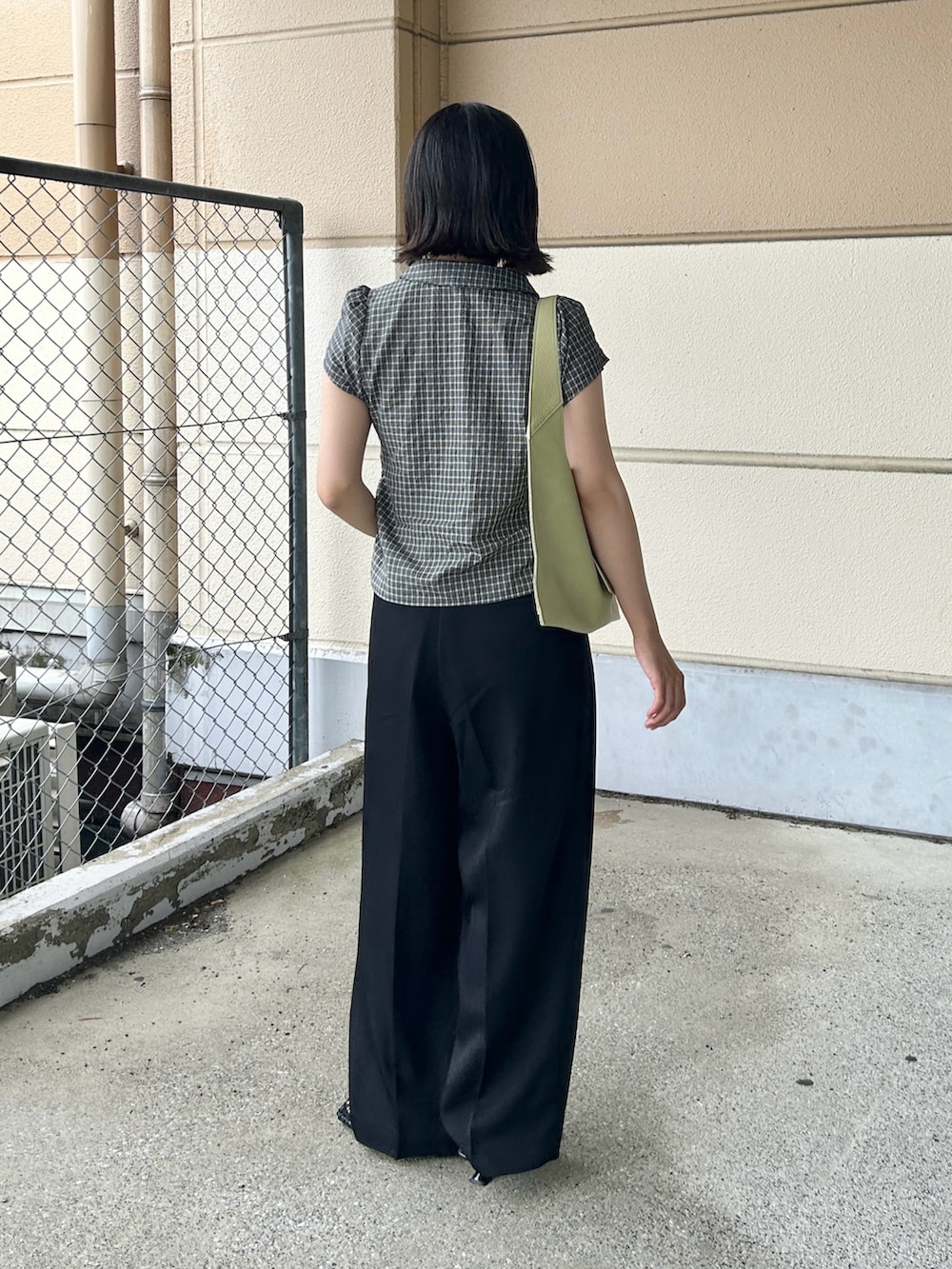 ブラック系のシャツ/ブラウス、ブラック系のスラックス、グリーン系のハンドバッグを着用したレディースの夏コーディネートの3枚目の写真
