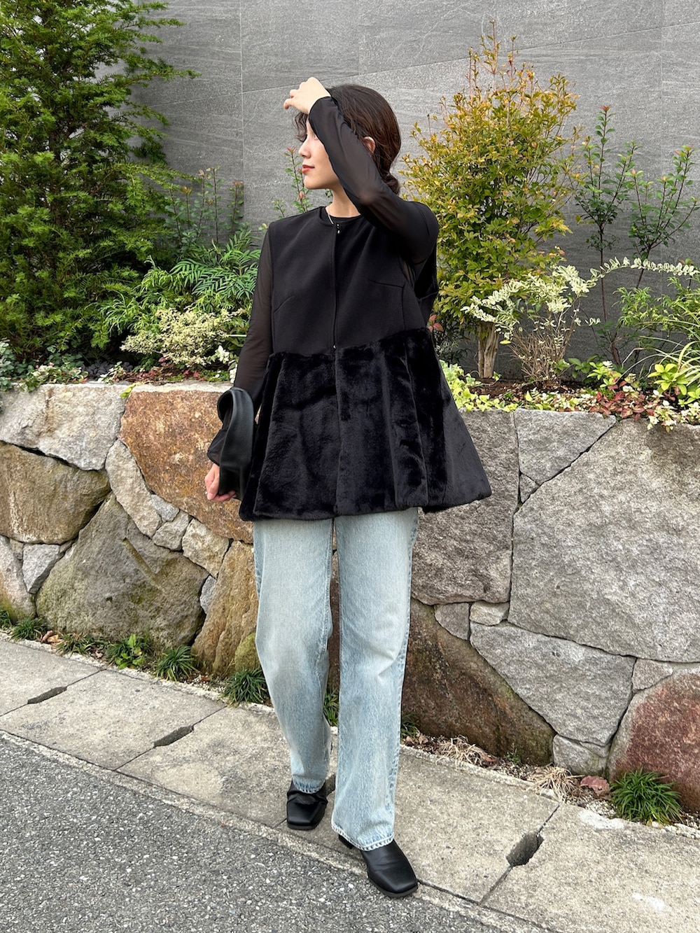 ブラック系のベスト、ブルー系のデニムパンツ、ブラック系のブーツを着用したレディースの秋コーディネートの3枚目の写真