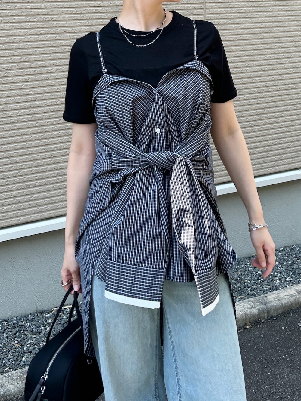 ブラック系のボストンバッグ、ホワイト系のシャツ/ブラウス、ブラック系のサンダルを着用したレディースの夏コーディネートの2枚目の写真