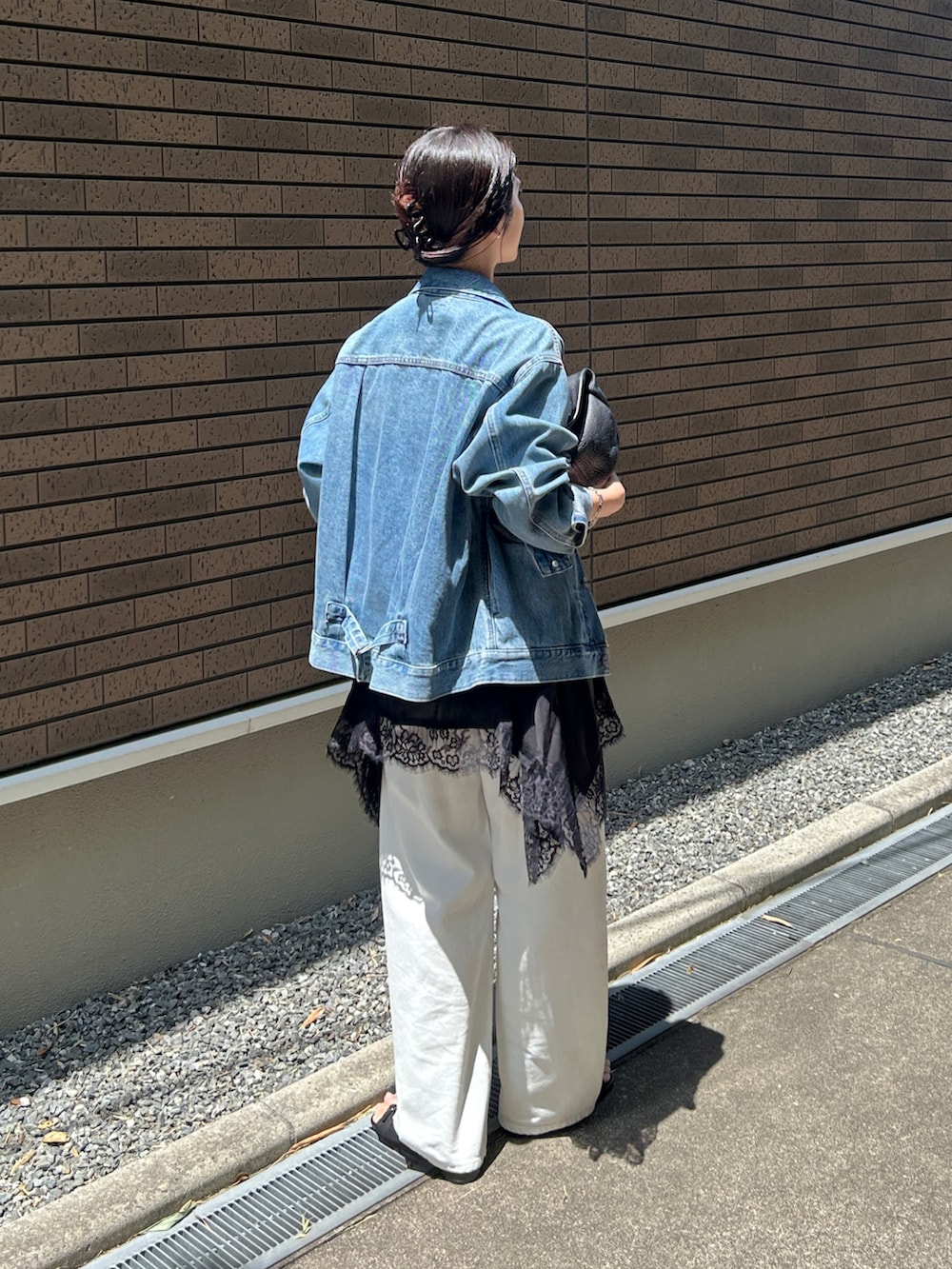 ブラック系のキャミソール、ブラック系のハンドバッグ、ホワイト系のデニムパンツを着用したレディースの春コーディネートの3枚目の写真