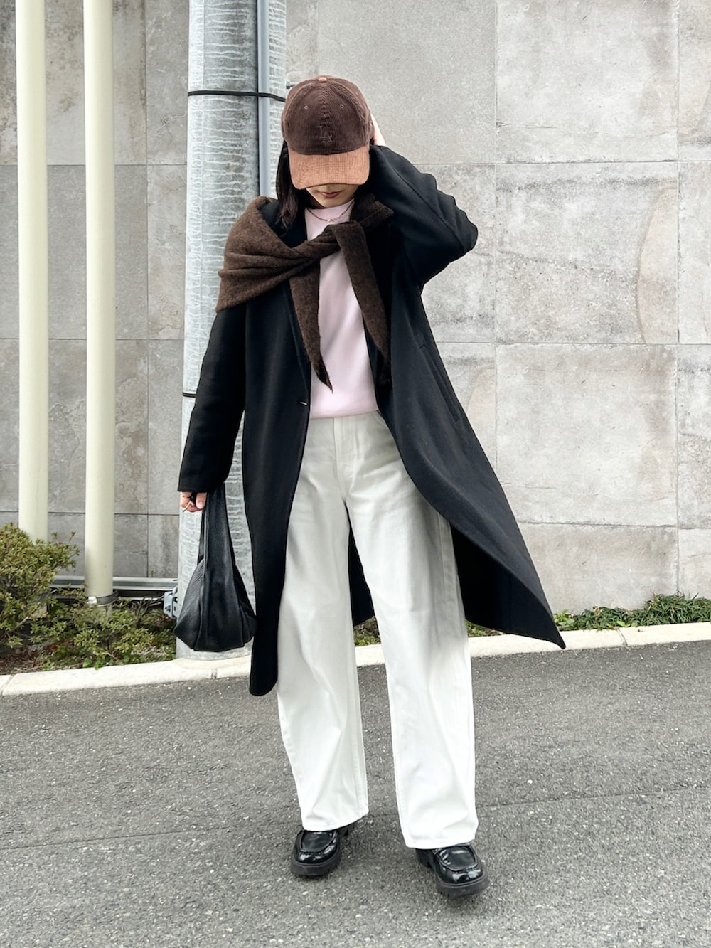 ブラック系のハンドバッグ、ブラック系のジャケット/アウター、ホワイト系のデニムパンツを着用したレディースの冬コーディネートの2枚目の写真