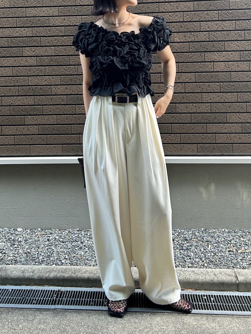 ブラック系のシャツ/ブラウス、ホワイト系のスラックス、ブラウン系のショルダーバッグを着用したレディースの夏コーディネートの4枚目の写真