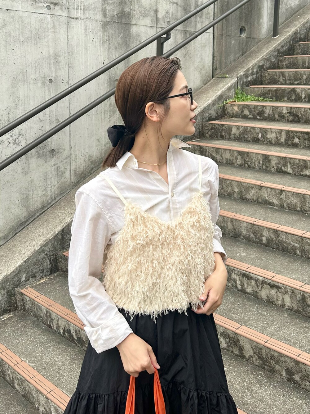 ホワイト系のベスト、ブラック系のスカート、ブラック系のローファーを着用したレディースの春コーディネートの2枚目の写真